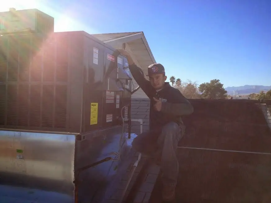 HVAC technician performing Air Duct Repair on a rooftop unit in Elba